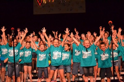 kids singing with hands raised in air