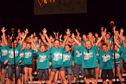 kids singing with hands raised in air